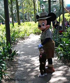 a person in a mickey mouse costume standing next to a child