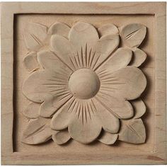 a white flower carved into the side of a wooden plaque with leaves and petals on it