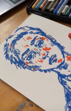 a drawing of a man's face is shown with crayons next to it