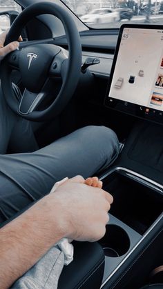 a man sitting in the driver's seat of a car using a tablet