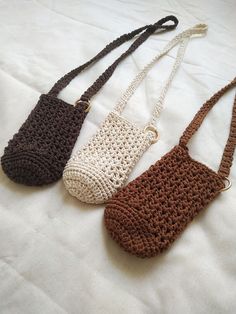 three crocheted purses sitting on top of a white bed next to each other