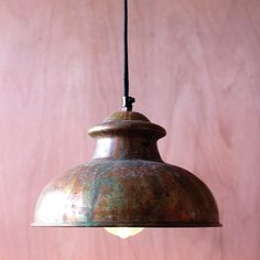 a metal light hanging from a pink wall