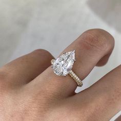 a woman's hand with a diamond ring on top of her finger and an engagement band