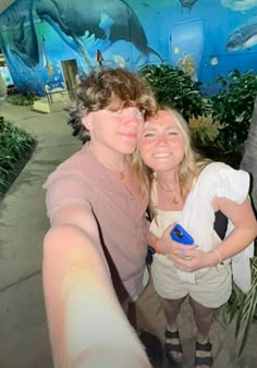 a man and woman are taking a selfie in front of a wall with dolphins painted on it