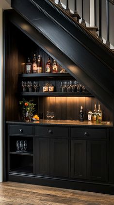 a bar under the stairs with liquor bottles and glasses