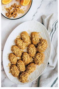 a white plate topped with cookies next to an orange and another plate filled with muffins