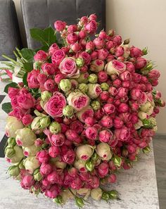 a bouquet of flowers sitting on top of a white table next to a black chair