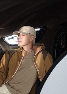 a man sitting in the back seat of a car wearing a hat and listening to music