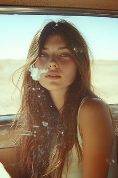 a woman sitting in the back seat of a car with her hair blowing in the wind