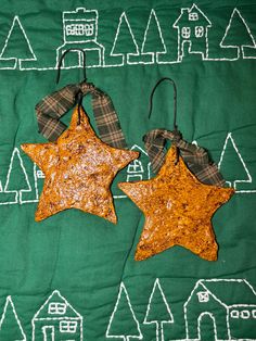 two star shaped cookies sitting on top of a green cloth covered in white and brown decorations