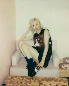 a woman sitting on top of a white couch next to pizza boxes and plates filled with doughnuts