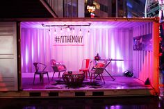 a stage set up with chairs and tables in front of a shipping container at night