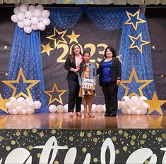 three women standing on stage in front of balloons and stars with the number twenty two