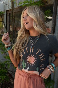 Embrace the dawn of a new day with our Rise With The Sun Graphic Tee, this cool graphic is perfect for all your boho ensembles and will have you wanting to wear it from sunrise to sunset! Comfortable, soft, mineral - washed tee shirt fabric Relaxed tee shirt silhouette Classic ribbed crew neckline and loose short sleeves So cute "Rise with the Sun" desert center graphic Pair with: Dora Low Back Seamless Bralette, High Hopes Slouchy Denim Overalls and Sacred Stone Beaded Bracelet Set. *Due to lig Bohemian Soft-washed Tops With Crew Neck, Bohemian Soft-washed Crew Neck Top, Bohemian Style Soft-washed Crew Neck Tops, Bohemian Crew Neck Washed Tops, Bohemian Washed Crew Neck Tops, Bohemian Acid Wash Crew Neck Top, Trendy Stonewashed Summer Tops, Bohemian Relaxed Fit Top For Everyday, Bohemian Tops With Relaxed Fit For Everyday