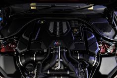 the engine compartment of a bmw car with its hood open and it's lights on