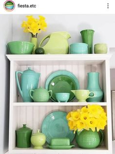 a shelf filled with green dishes and yellow flowers