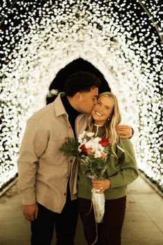 a man and woman standing next to each other in front of a tunnel with lights