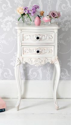 a white table with two drawers and flowers on top