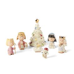 a group of figurines that are standing in front of a white christmas tree