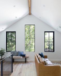 a living room filled with furniture next to two large windows on top of a wooden floor