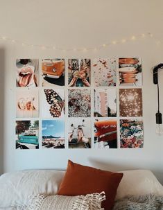 a white bed topped with lots of pictures on the wall next to a light fixture