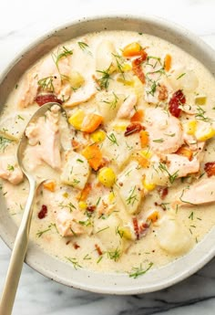 a white bowl filled with chicken, potatoes and carrots on top of a marble counter