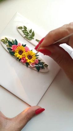 a woman's hand holding a pen and drawing flowers on a piece of paper