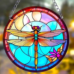 a stained glass window with a dragonfly hanging from it's side and flowers on the outside