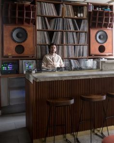 a man sitting at the bar in front of some speakers and bookshelves,