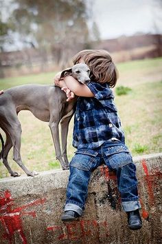 a little boy hugging his dog on the side of a wall with words above it