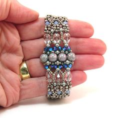 a hand holding a beaded bracelet on it's fingers