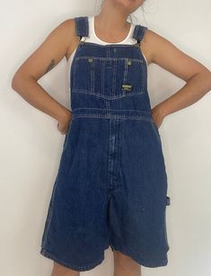 OshKosh B'Gosh dark blue denim overalls. Shorts. Made in USA. Union made. Green stitching. Triple cover. Vintage. Label: OshKosh Material: cotton Condition: in good vintage condition, mild wear from age. Appears to have been temporarily hemmed 1" off the shorts, could be easily undone if desired. Measurements lying flat, double the armpit, waist, and hips. Length (bib to hem): 33" Waist: 21" Hips: 22" Inseam: 9" Short Dungarees Outfit Winter, Dungarees Outfit Winter, Short Dungarees Outfit, Overall Shorts Outfit, Dungaree Outfit, Thrift Wishlist, Longer Shorts, Baggy Overalls, Blue Denim Overalls