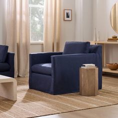 a living room with two blue chairs and a coffee table in front of a window