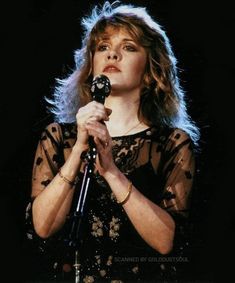 a woman holding a microphone in her right hand