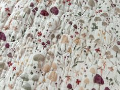 a close up view of a quilted bed spread with flowers and leaves on it