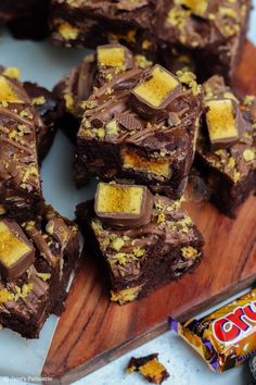 there are many pieces of brownies on the cutting board next to some candy bars