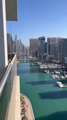 boats are docked in the water next to tall buildings and skyscrapers, as seen from an apartment balcony