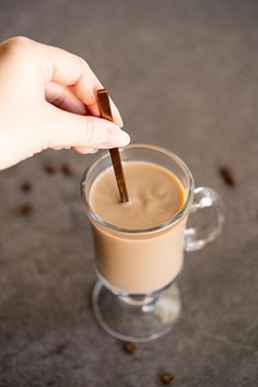 a person is holding a spoon in a glass cup