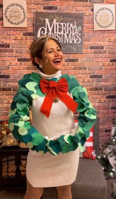 a woman in a christmas sweater with a wreath around her neck and red bow tie