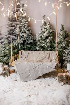 there is a baby crib in the snow next to some christmas trees and lights