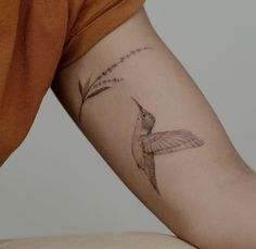 a small hummingbird tattoo on the right arm and shoulder, with stars in the background