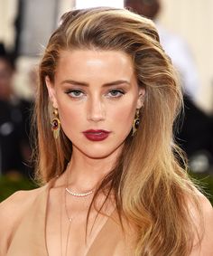 a woman with long blonde hair wearing red lipstick and gold dress at the met ball