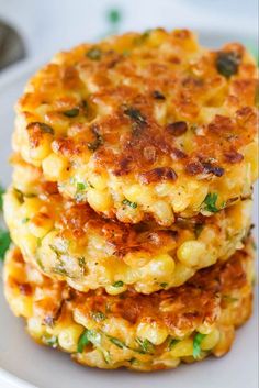 three crab cakes stacked on top of each other in a white plate with green garnish