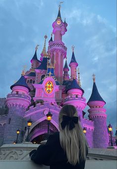 a woman standing in front of a pink castle