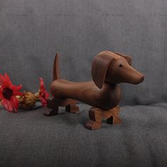 a wooden dachshund figurine next to a flower on a couch