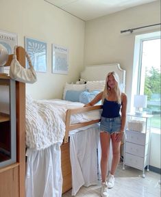 a woman standing next to a bed in a bedroom