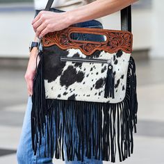 Introducing our one-of-a-kind western-style leather Bannok Hand Tooled Handles Cowhide Crossbody Bag with fringes and hand-tooled handles. This stunning bag is made from high-quality leather and features intricate hand-tooled detailing. The fringes add a touch of bohemian flair, making it the perfect accessory for any modern cowgirl. The spacious interior allows you to carry all your essentials, while the sturdy strap makes it easy to carry on your shoulder or across your body. Whether you're he Hand Tooled Leather Bags For Rodeo, Leather Bags With Concho For Everyday Use, Western Leather Bags For Rodeo, Western Leather Bags With Concho Details, Western Leather Bag With Fringe, Western Style Bags With Fringe For Everyday Use, Western Style Fringed Bags For Everyday Use, Western Style Fringe Bags For Everyday Use, Modern Cowgirl