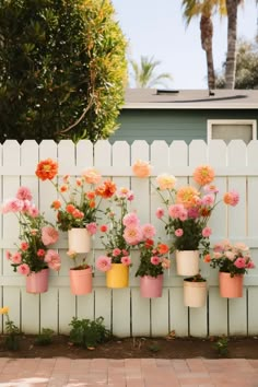 several potted flowers are hanging on a white fence