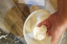 a person is holding something in their hand on the floor next to a white bowl