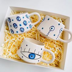 three coffee mugs with eyes on them in a box